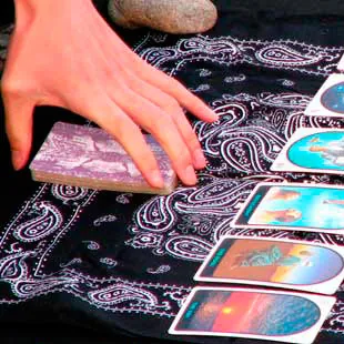 Mano cortando el mazo del tarot sobre un pañuelo negro