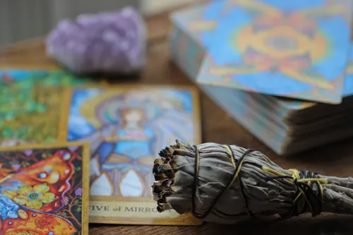 Cartas del tarot junto a un atado de salvia y un cuarzo