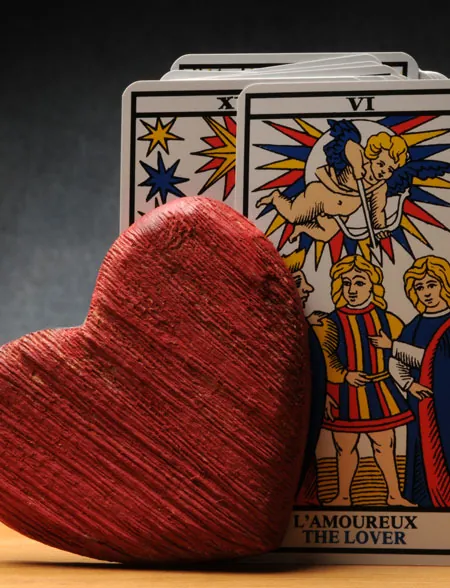 Corazón de madera junto a la carta de El Enamorado del tarot